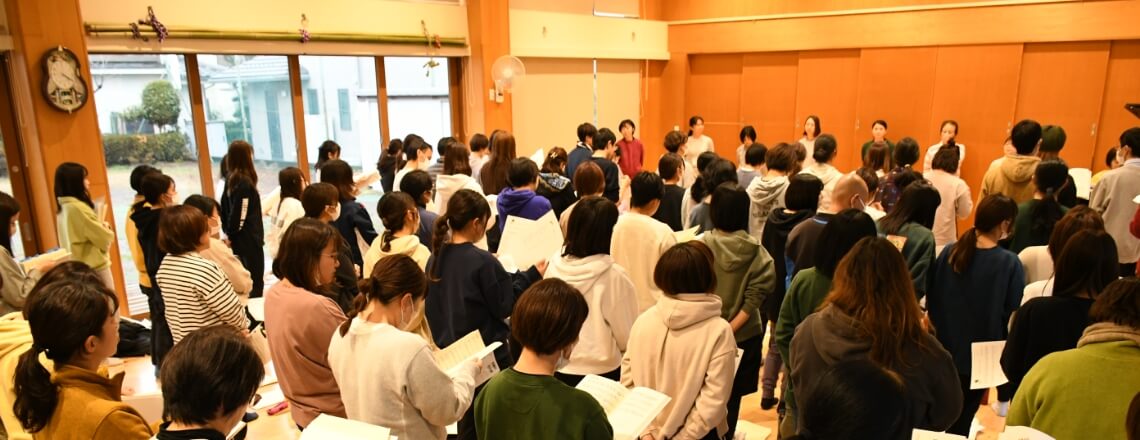 写真：教室内に先生たちが集まり、研修の説明を受ける様子