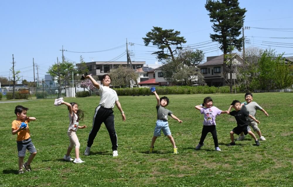 写真：青い芝生が広がる広場でボールを思いっきり投げて遊ぶ様子