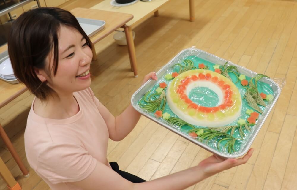 写真：先生が豪華に盛り付けられたケーキを持ってきた様子