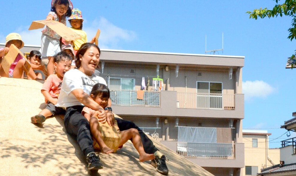 写真：小高い丘で段ボールを使ってソリを楽しむ様子