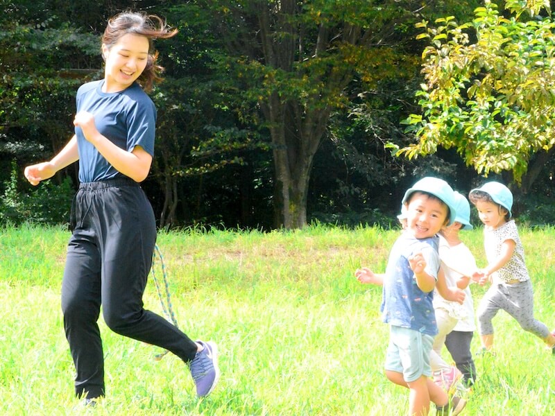 写真：自然豊かな屋外にてかけっこして楽しむ様子